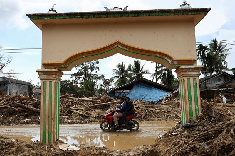 Indonesians climb over logs in walk to aid centre as flood deaths rise over 900
